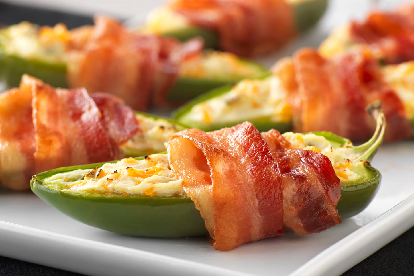 Bacon-wrapped jalapeño poppers on a white plate