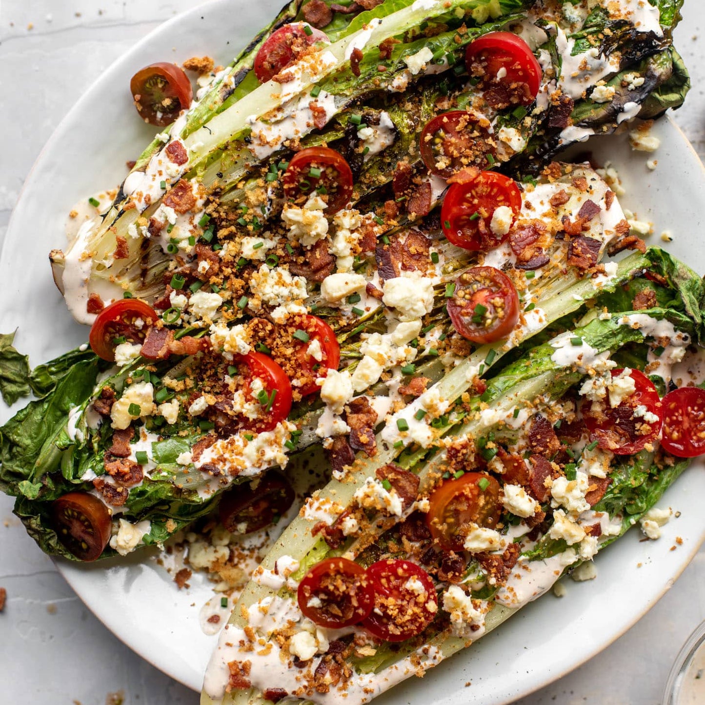 Plated salad with romaine, tomatoes, and crumbled cheese on a white plate.