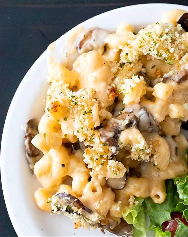 Macaroni and cheese with mushrooms and broccoli on a white plate