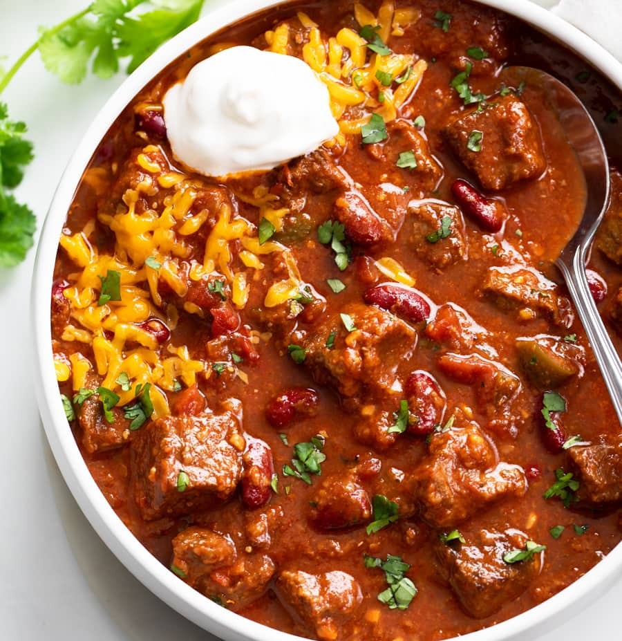 Bowl of chili with beans, rice, and sour cream on a white background