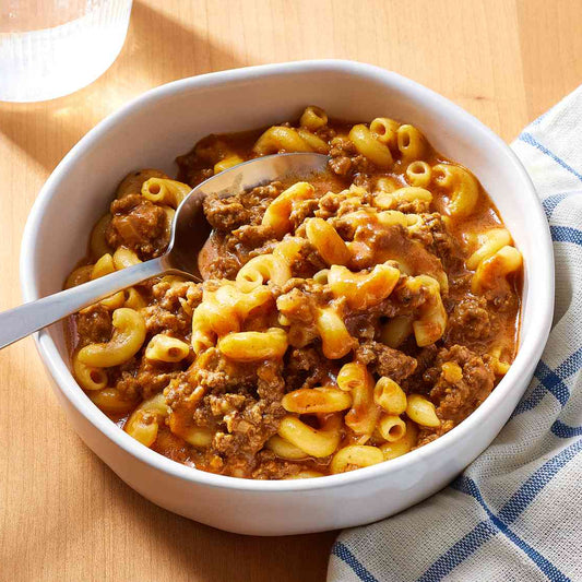 Bowl of macaroni and cheese with a spoon on a wooden table