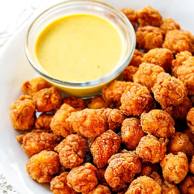 Fried chicken bites on a plate with a small bowl of dipping sauce.