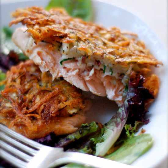 Salmon fillet with crispy skin on a bed of greens with a fork.