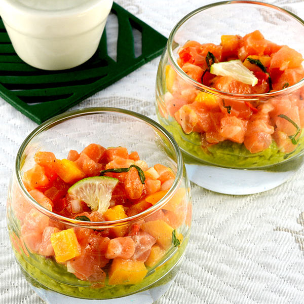 Two glass cups with watermelon salad on a white surface with a cactus plant in the background.