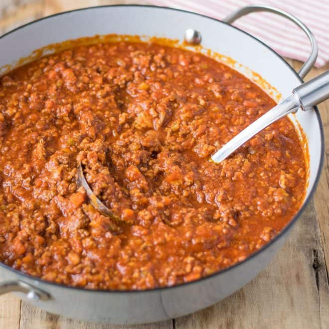 Bowl of red bolognese sauce on a wooden surface