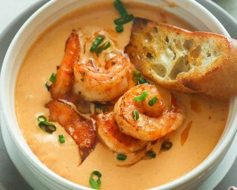 Shrimp and grits dish with bread and green onions in a white bowl.