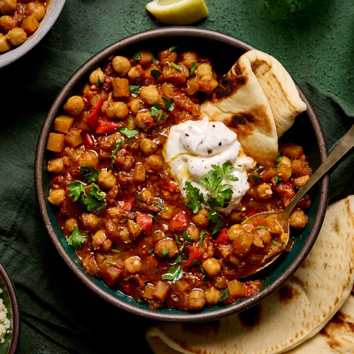 Chickpea curry with naan bread and yogurt sauce on a dark surface